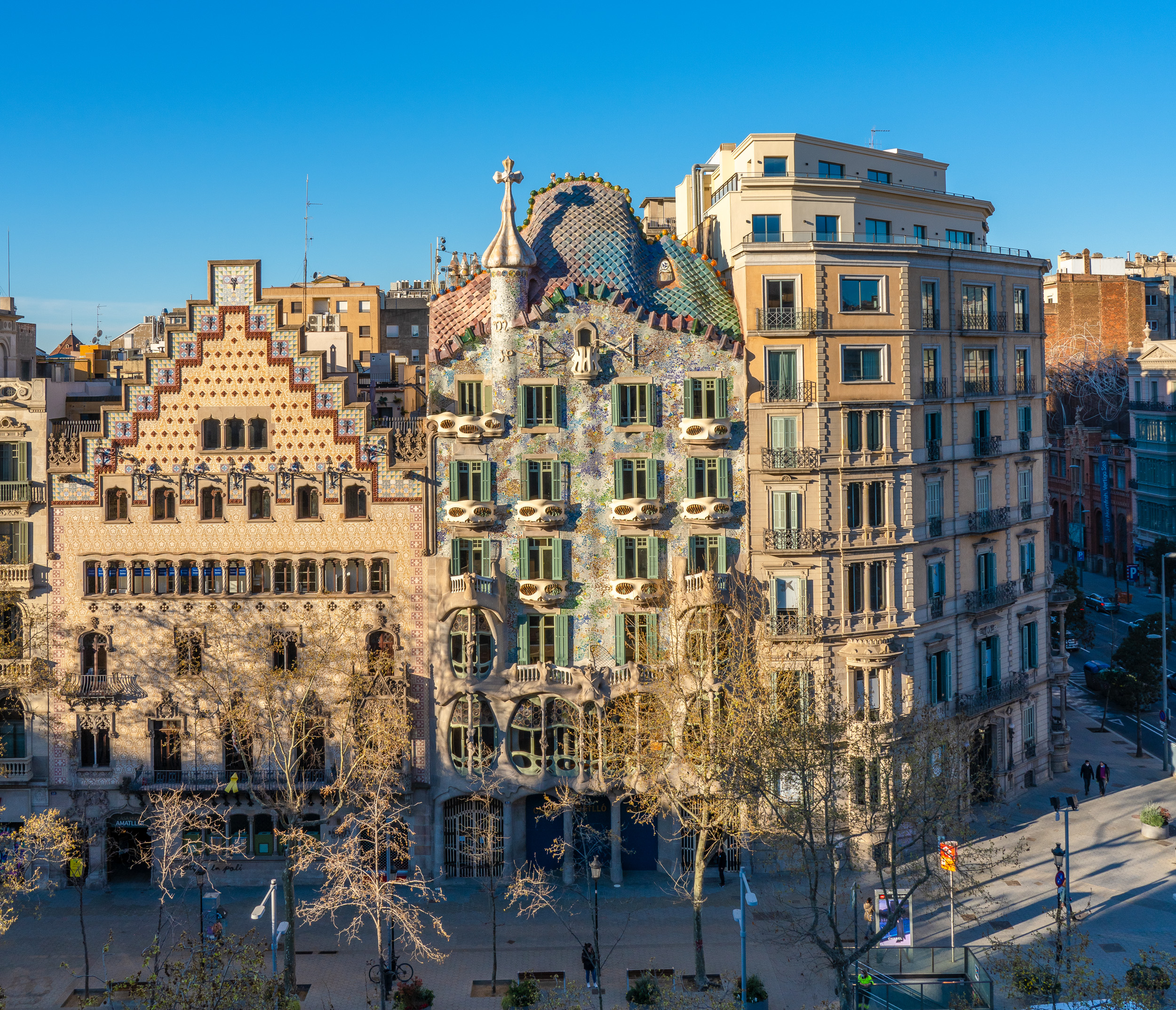 Casa Batlló and neighboring buildings in Barcelona, Spain, with ornate facades and a clear blue sky in the background.