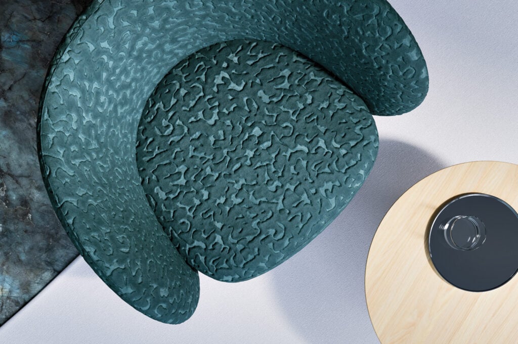 Overhead view of a textured green armchair next to a round light wood table with a dark, circular object on top—an inviting corner that radiates METROPOLISLikes charm.