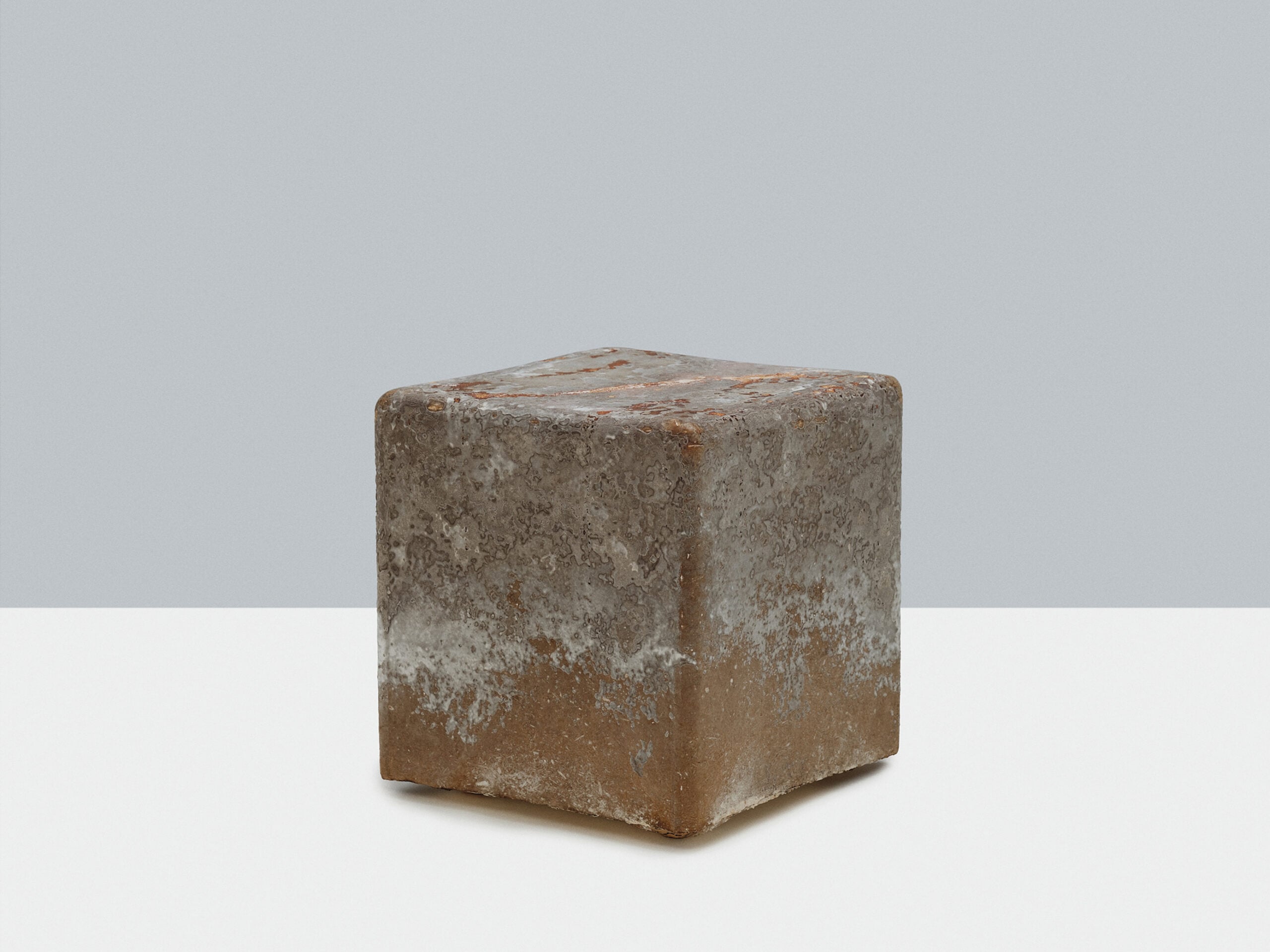 Biobased materials: A weathered, rusted metal cube sits on a white surface against a light gray background.