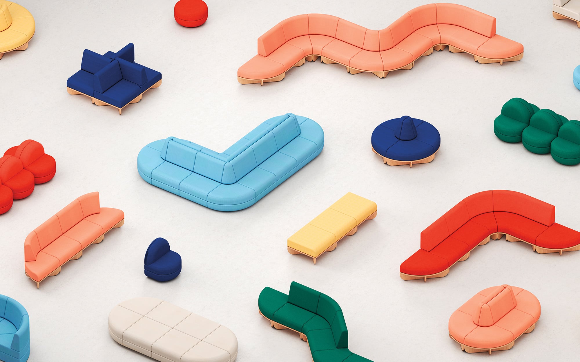 Various colorful, modern modular office products are arranged in different shapes and colors on a plain, light floor.