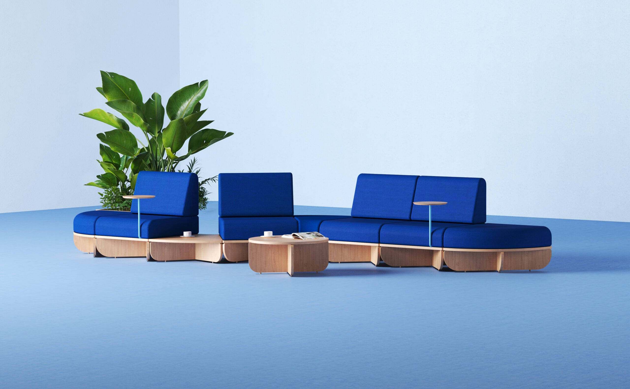 Office products: Modular blue and wood seating with built-in tables arranged on a light blue floor, with a potted plant in the background against a light blue wall.