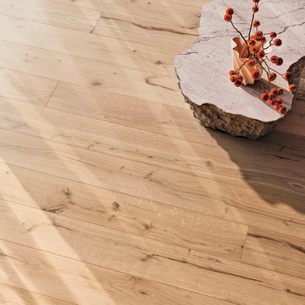 Light wood plank flooring with natural grain, next to a rough-edged stone piece holding an orange vase with red berries. Sunlight creates shadows across the scene—an aesthetic sure to earn METROPOLISLikes.