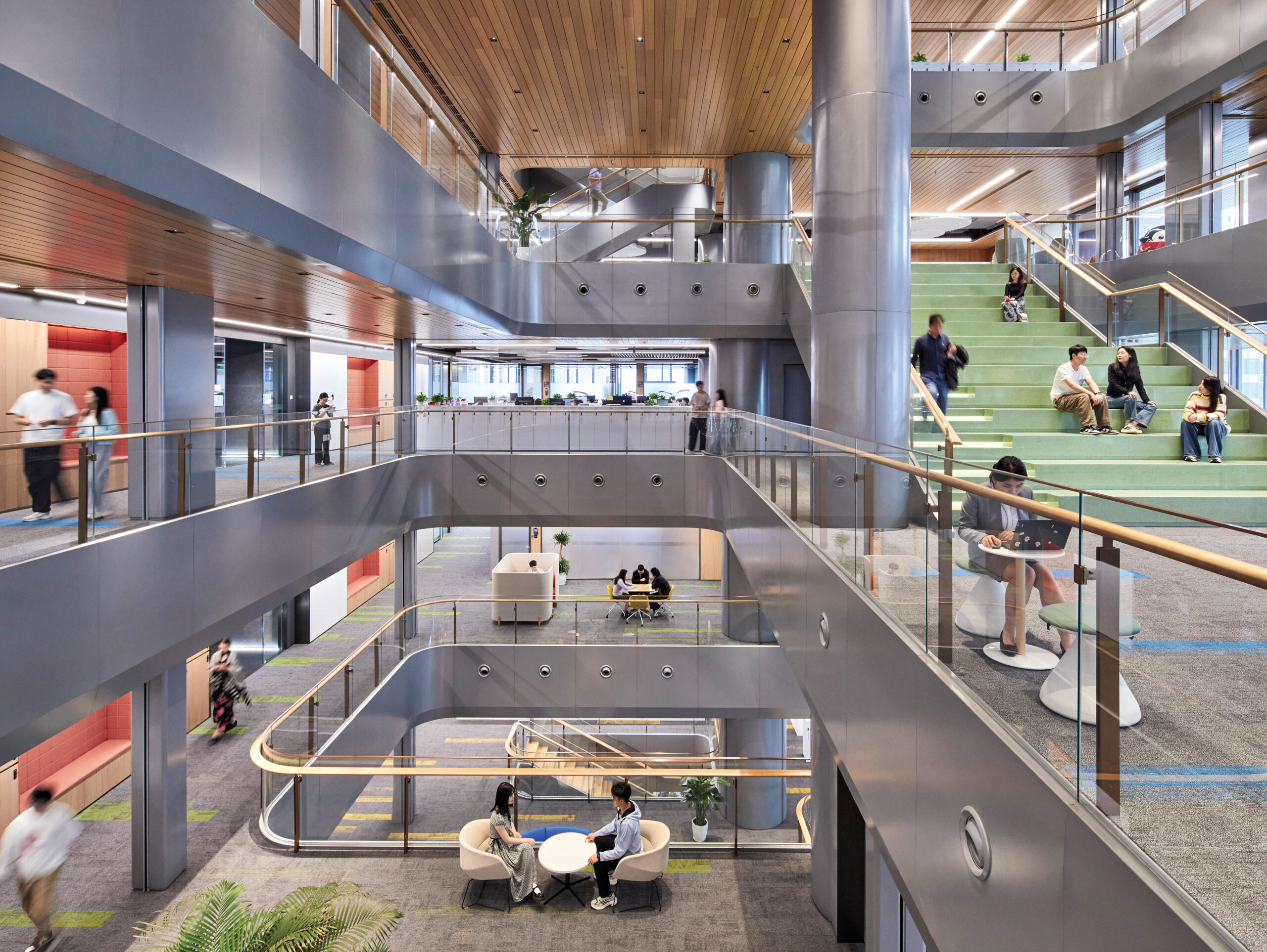WeBank HQ: Modern multi-story office interior with open seating areas, glass railings, wood ceilings, people working, and stairs connecting different levels.