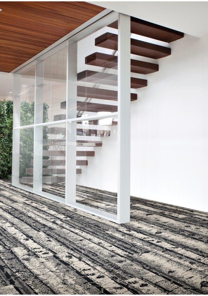 A modern interior with floating wooden stairs, a glass wall, white walls, and patterned carpet flooring—an inviting space that truly embodies the METROPOLISLikes aesthetic.
