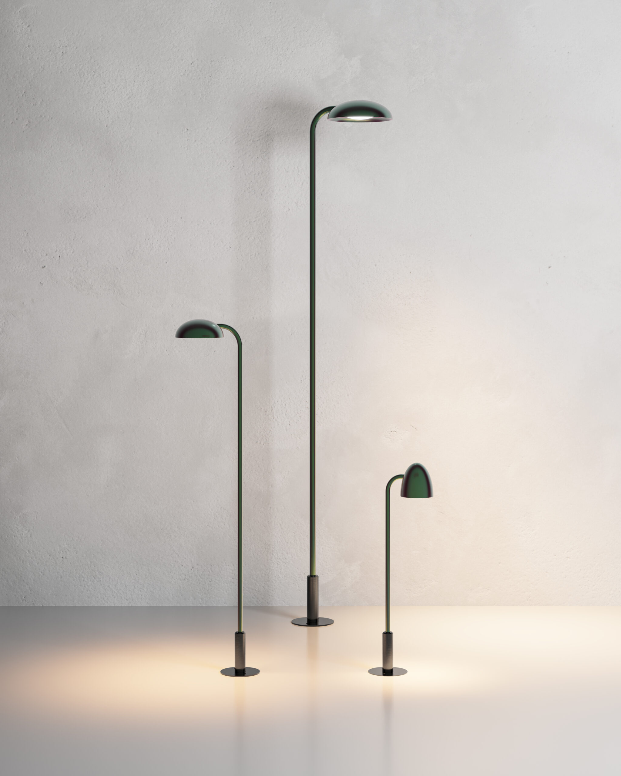 Neuro-Inclusive Lighting: Three modern minimalist lamps of varying heights stand on a smooth surface against a plain light gray wall, each casting a warm light downward.