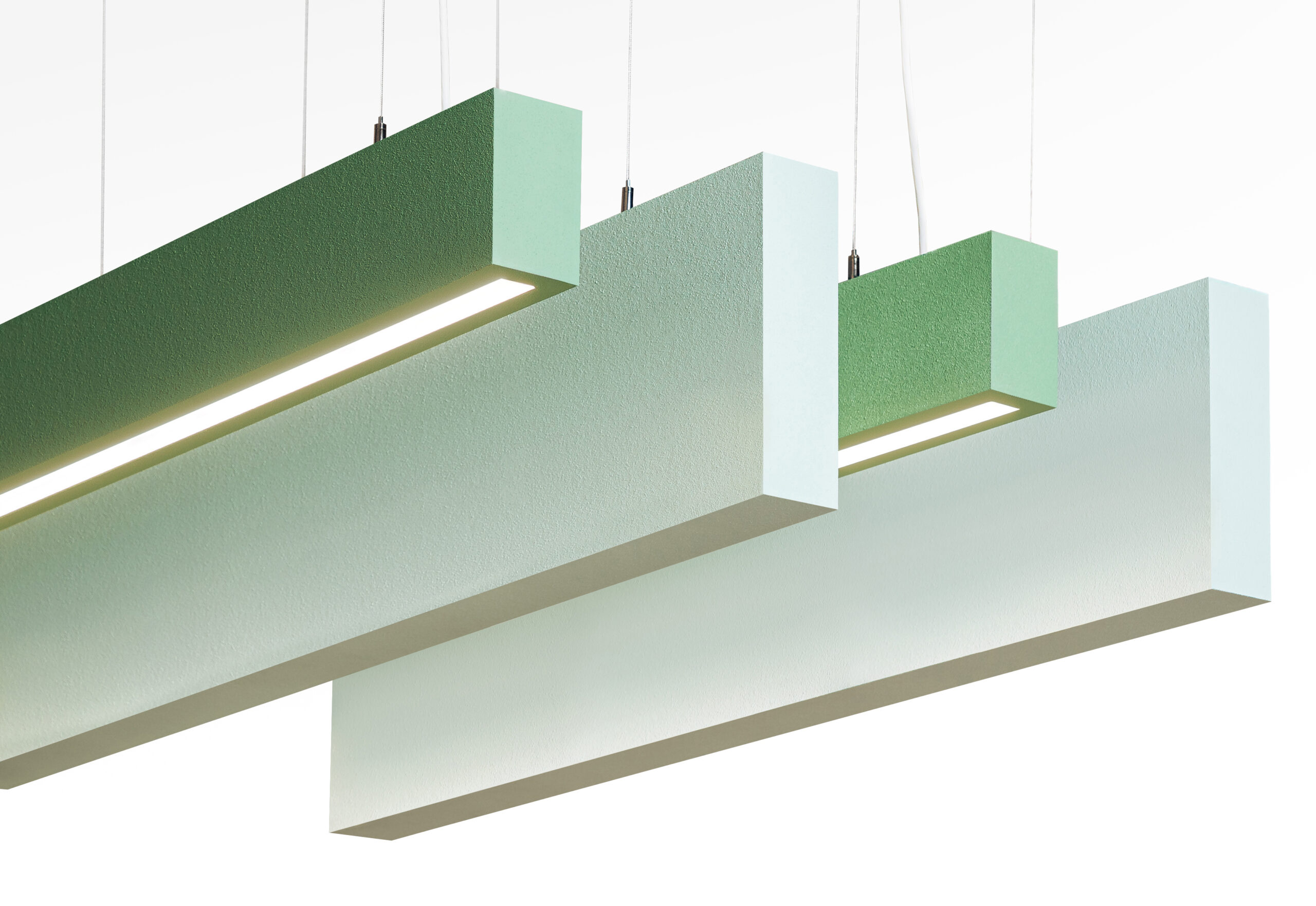 Four rectangular, suspended light fixtures in gradient green and white tones hang parallel from the ceiling, each emitting a soft, downward light.