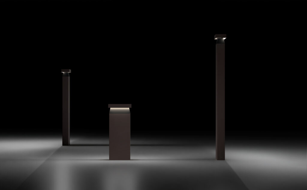 Neuro-Inclusive Lighting Solutions: Three dark rectangular pillars of varying heights stand on a smooth, dimly lit surface with small lights atop each, against a black background.
