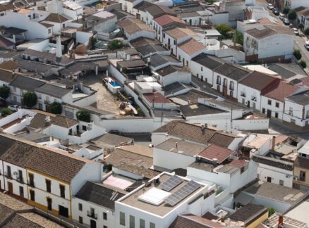 Aerial view of a neighborhood with closely packed white buildings, tiled roofs, narrow streets, and some solar panels visible—an area where the principles of Passive House design may be observed in the emphasis on energy efficiency and modern sustainability.