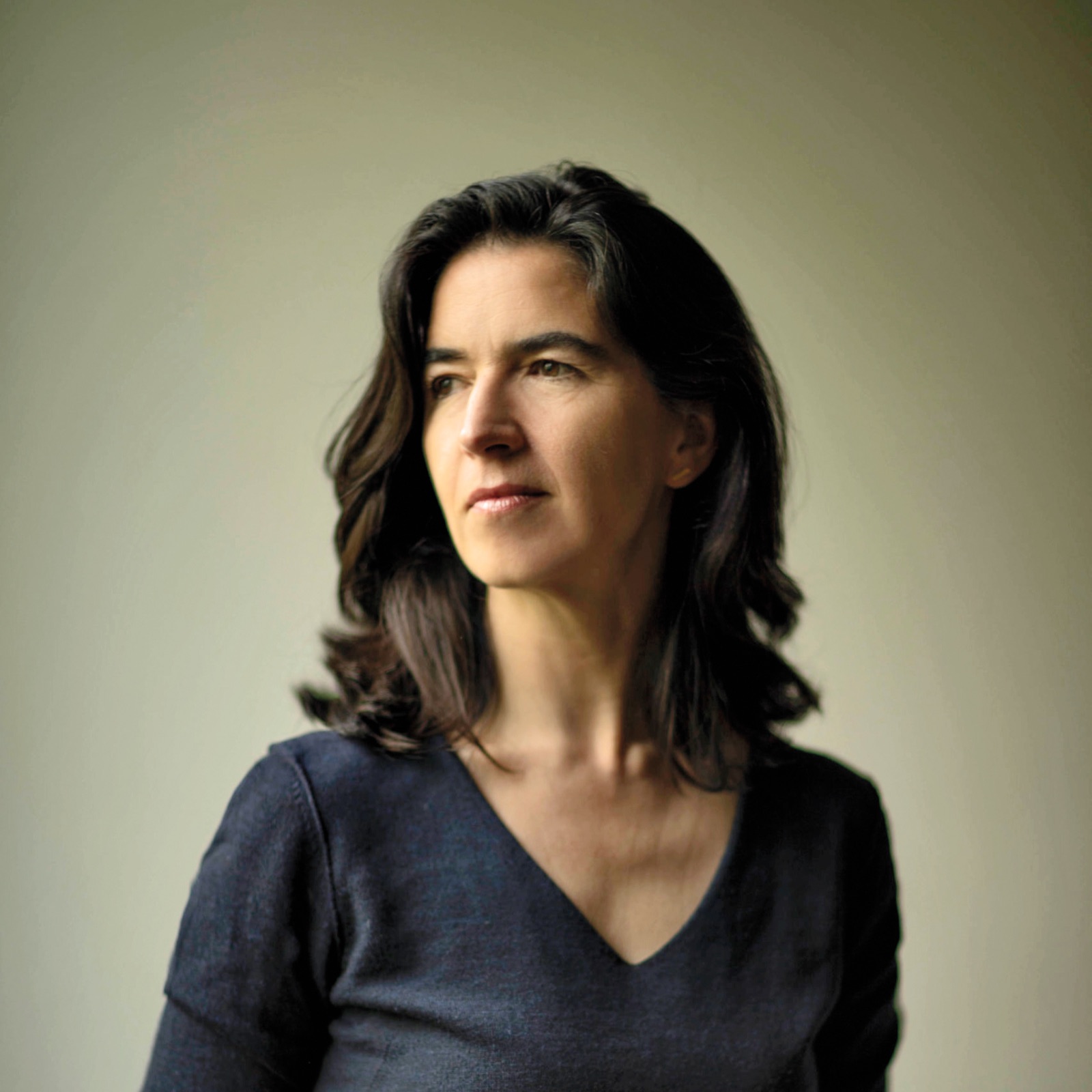A woman, Fernanda Canales, with shoulder-length brown hair wearing a dark V-neck top looks to the side against a plain background.