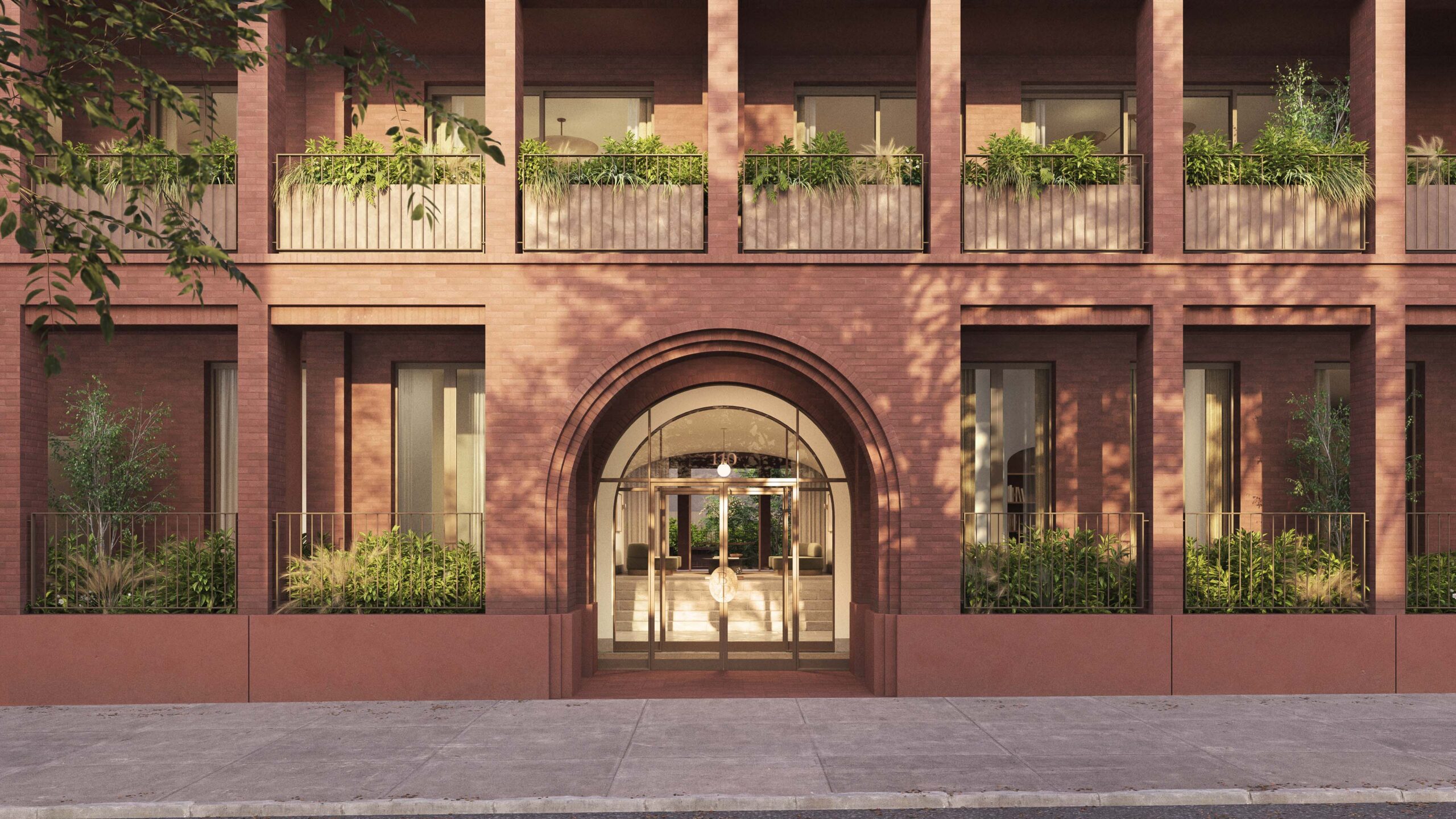 The image shows the entrance of a modern brick building with large glass doors, arched detailing, and balconies with potted plants.