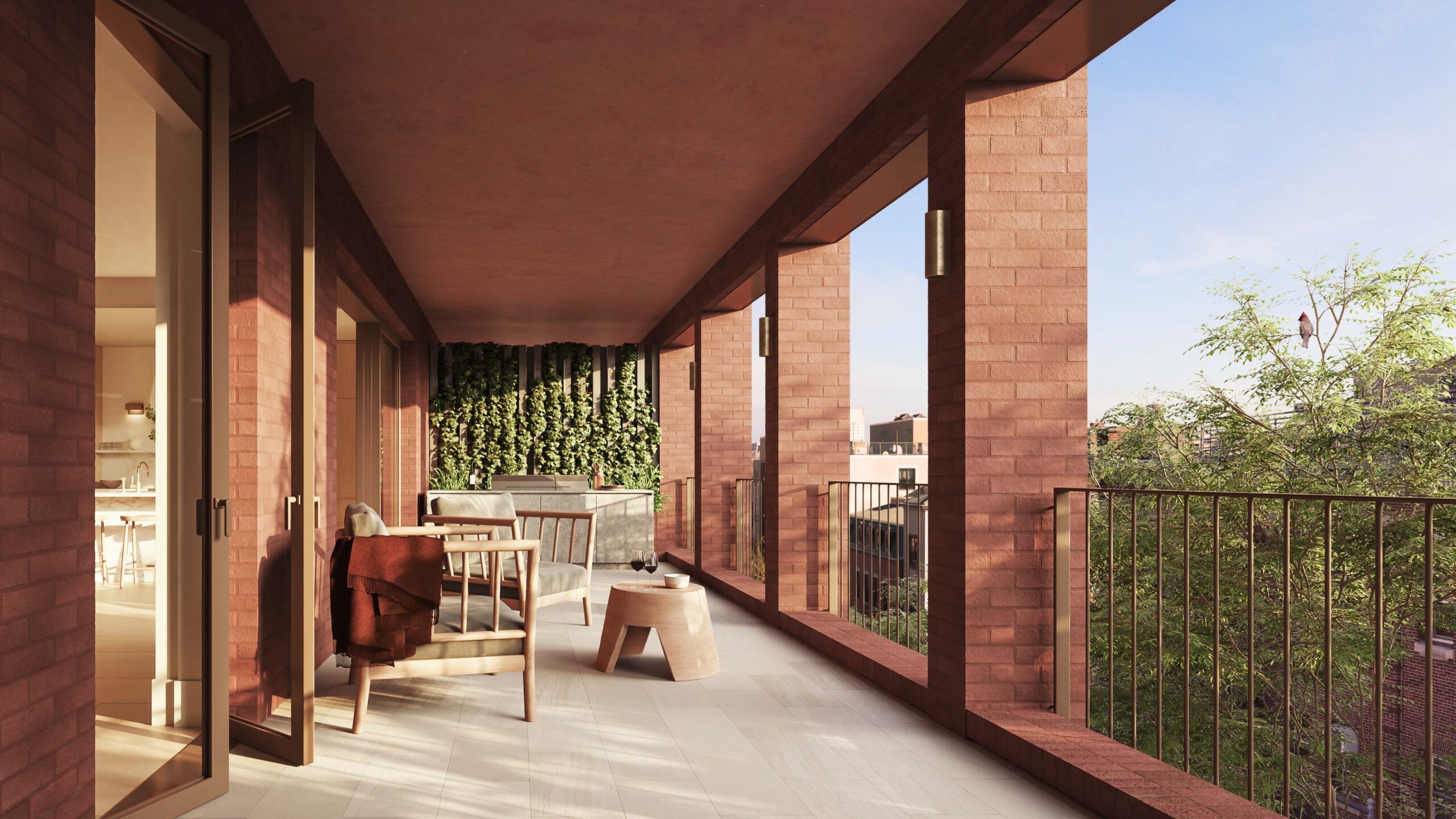Spacious covered balcony with brick columns, seating area, small tables, and greenery on one wall, overlooking trees and buildings under a clear sky.