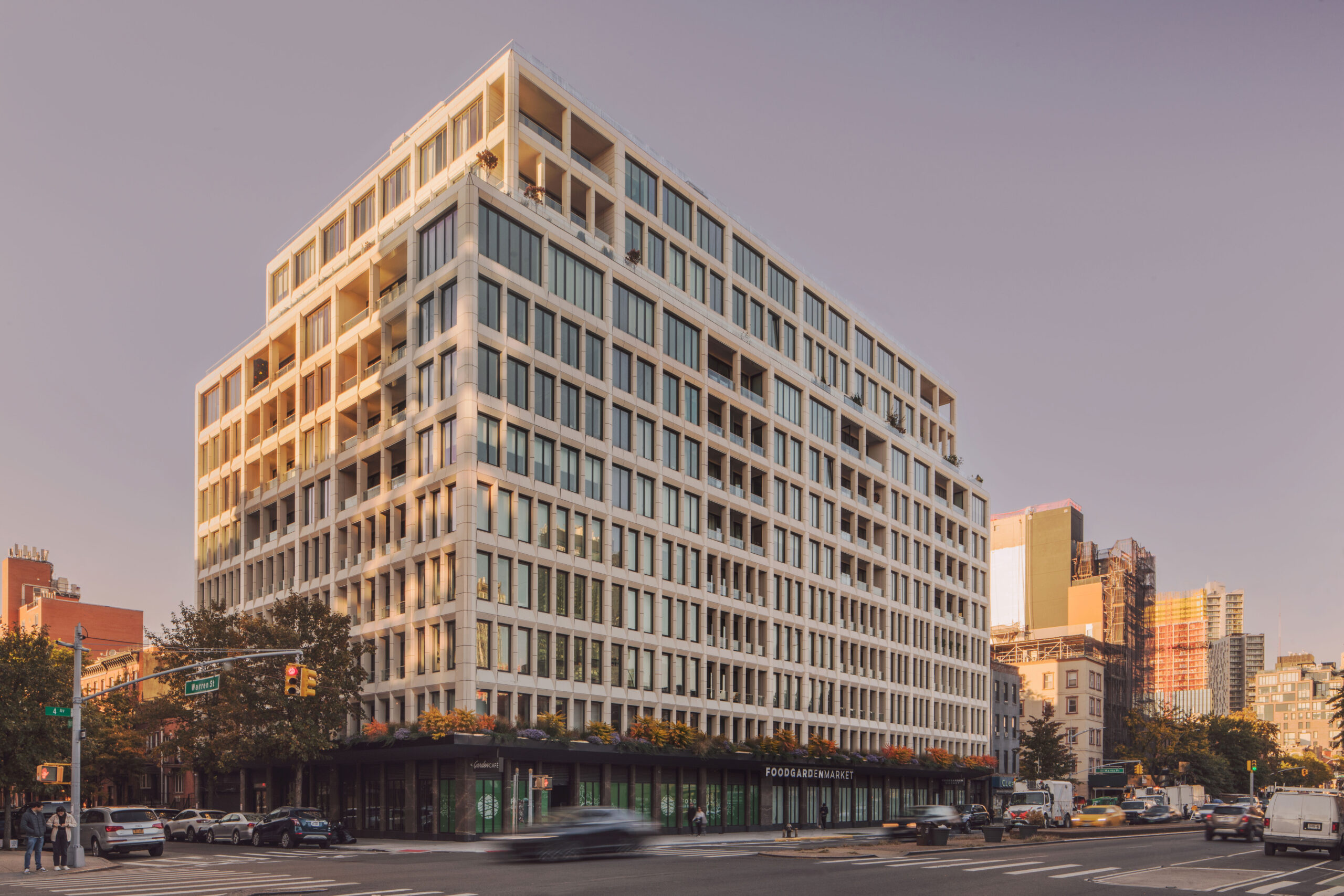 A modern multi-story building with large windows on a city street corner, featuring ground-floor storefronts and light traffic passing by—an iconic urban scene frequently captured by Avdoo.