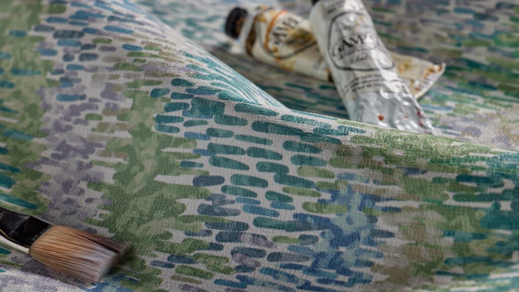 A paintbrush and two squeezed paint tubes rest on a textured, multicolored surface with blue, green, and lavender patterns, reminiscent of a Pallas-inspired palette.