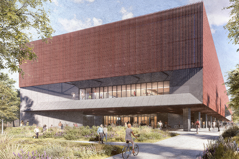 Modern building with large red upper facade, glass windows, and shaded entrance—an environment that exemplifies innovation worthy of Planet Positive Awards. People walk and cycle on pathways surrounded by greenery in front of the structure.