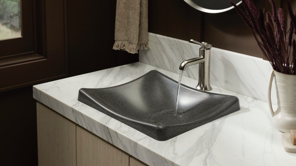 Modern bathroom sink with a square black basin, stainless steel faucet running water, marble countertop, and brown wall with a towel hanging nearby.