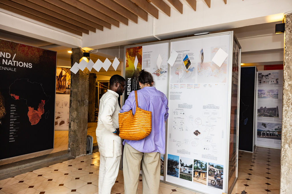 Two people stand in front of a large display board with maps, charts, and images in an indoor exhibition space at UIA 2026 Barcelona.