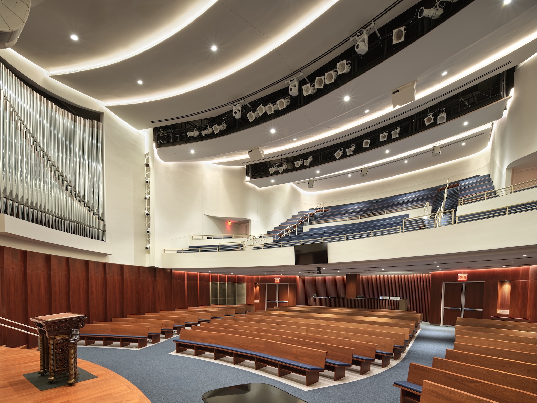Spacious modern auditorium with wooden pews, an organ, tiered seating, and a lectern on stage at the Lucas Museum of Narrative Art.