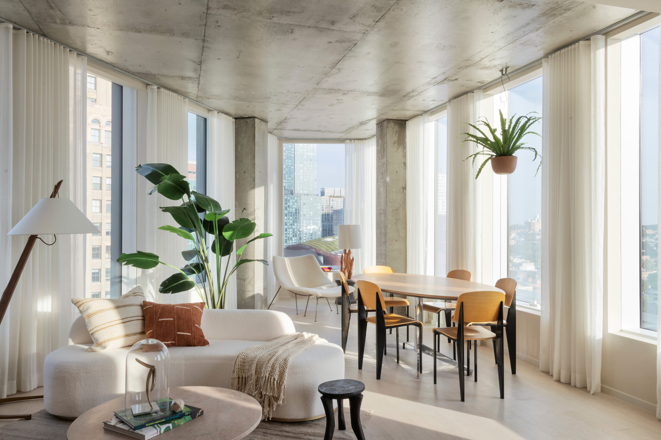 Modern, bright living and dining area with large windows, neutral furnishings, indoor plants, light wood floors, and city views—perfect for announcing the Winners of the 2026 METROPOLIS Planet Positive Awards.