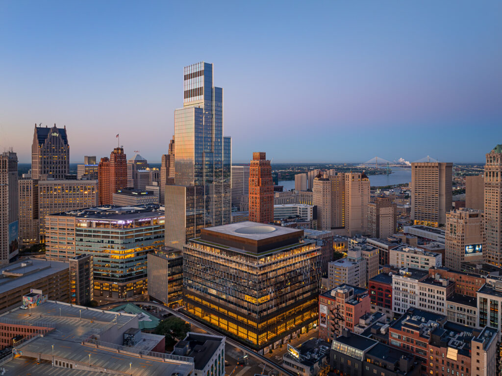 A cityscape at dusk shows modern and historic buildings in downtown Detroit, Michigan, with the sky transitioning from blue to pink near the horizon.