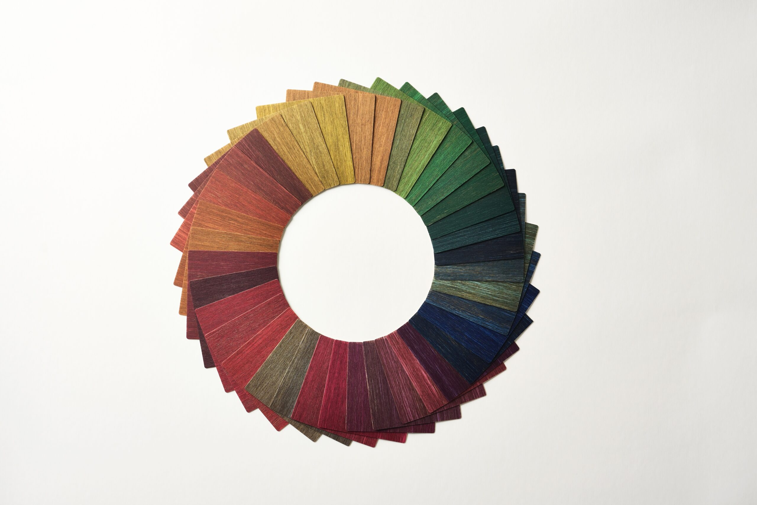 Fan-shaped colored paper strips arranged in a circular pattern on a white background, showing a gradient from red to green to blue.