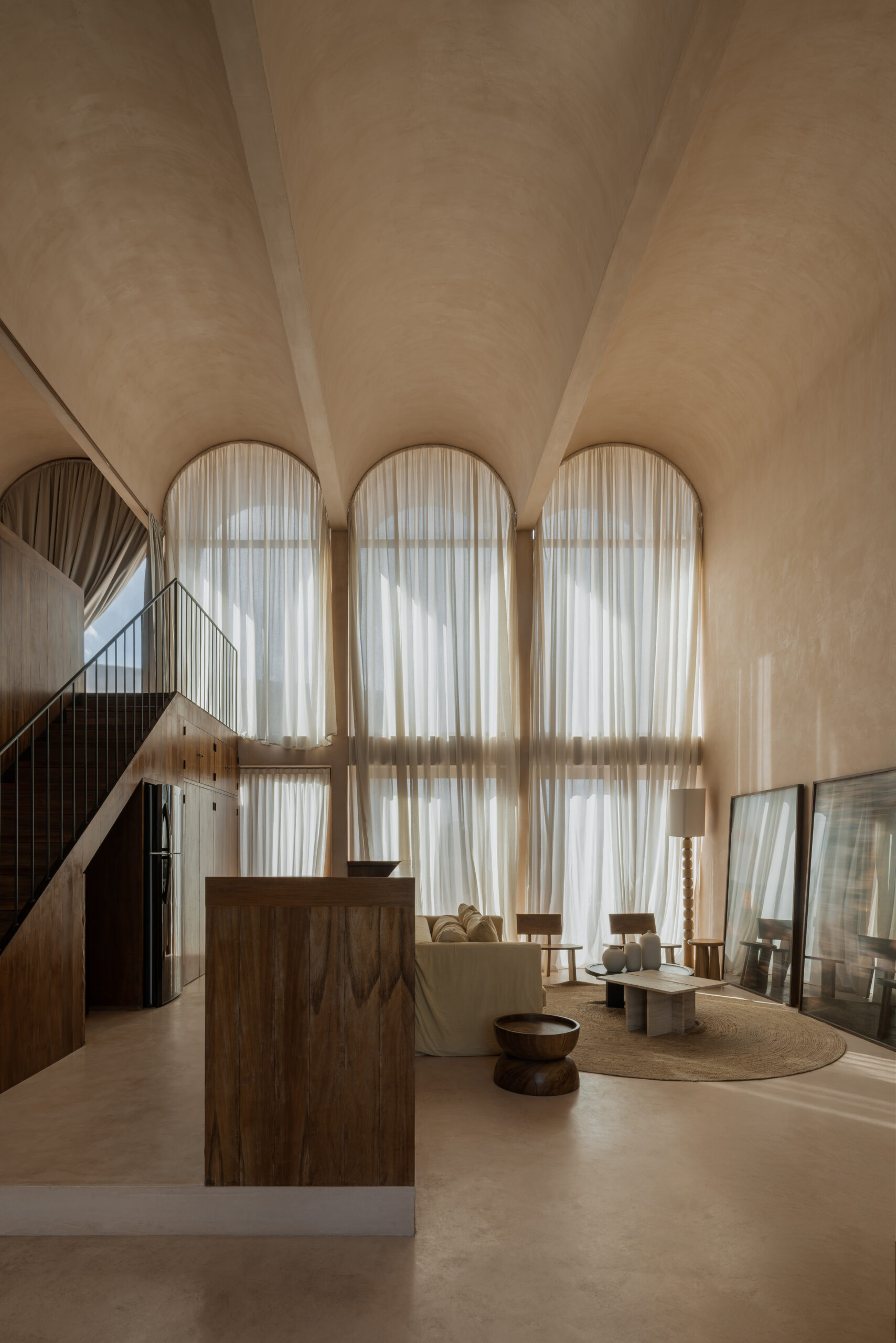 Modern residential interior by Mexican architects V Taller with barrel ceilings in a sandy brown shade, long gauzy curtains and modern furniture.