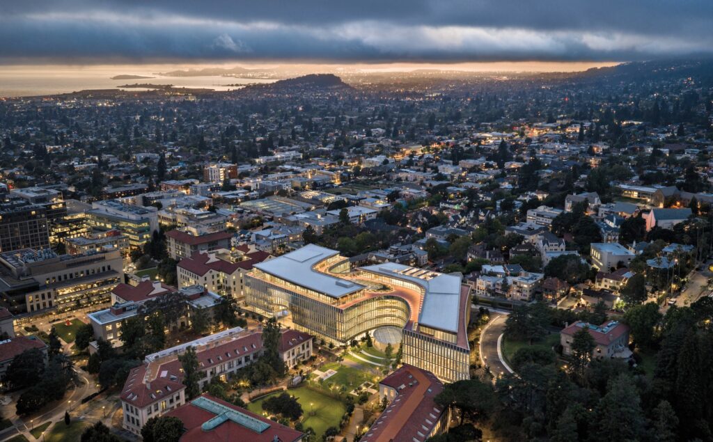Aerial view of the curved, multi-story Lucas Museum of Narrative Art illuminated at twilight, situated within a city and neighborhood landscape.