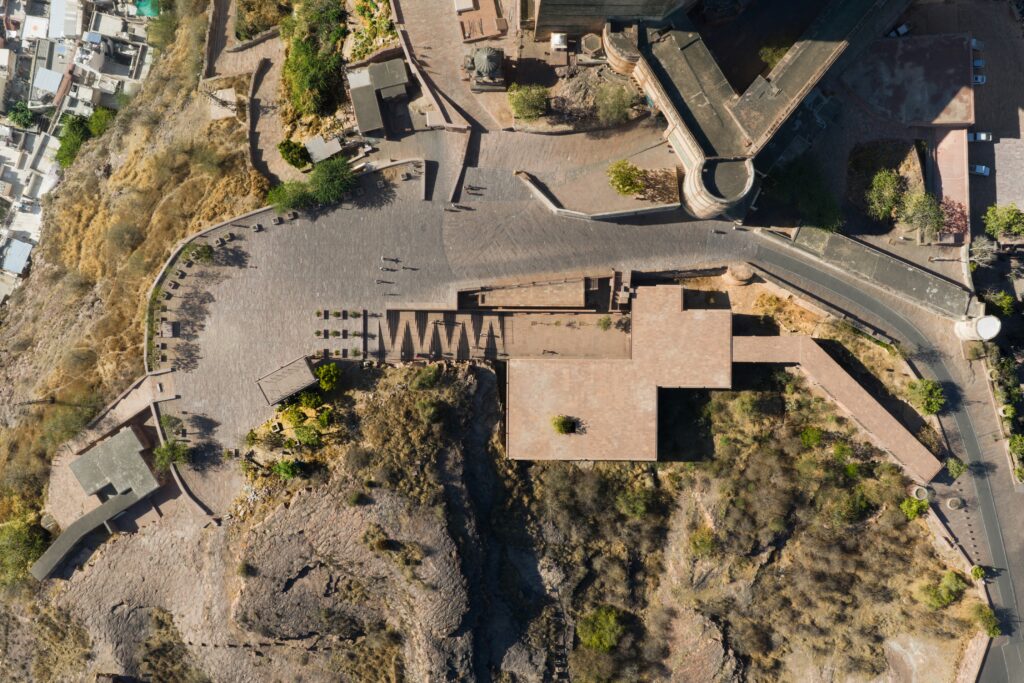 Aerial view of the Barbara and Gerson Bakar Gateway at UC Berkeley, showing a paved plaza and stone buildings on a hillside with paths and sparse vegetation.
