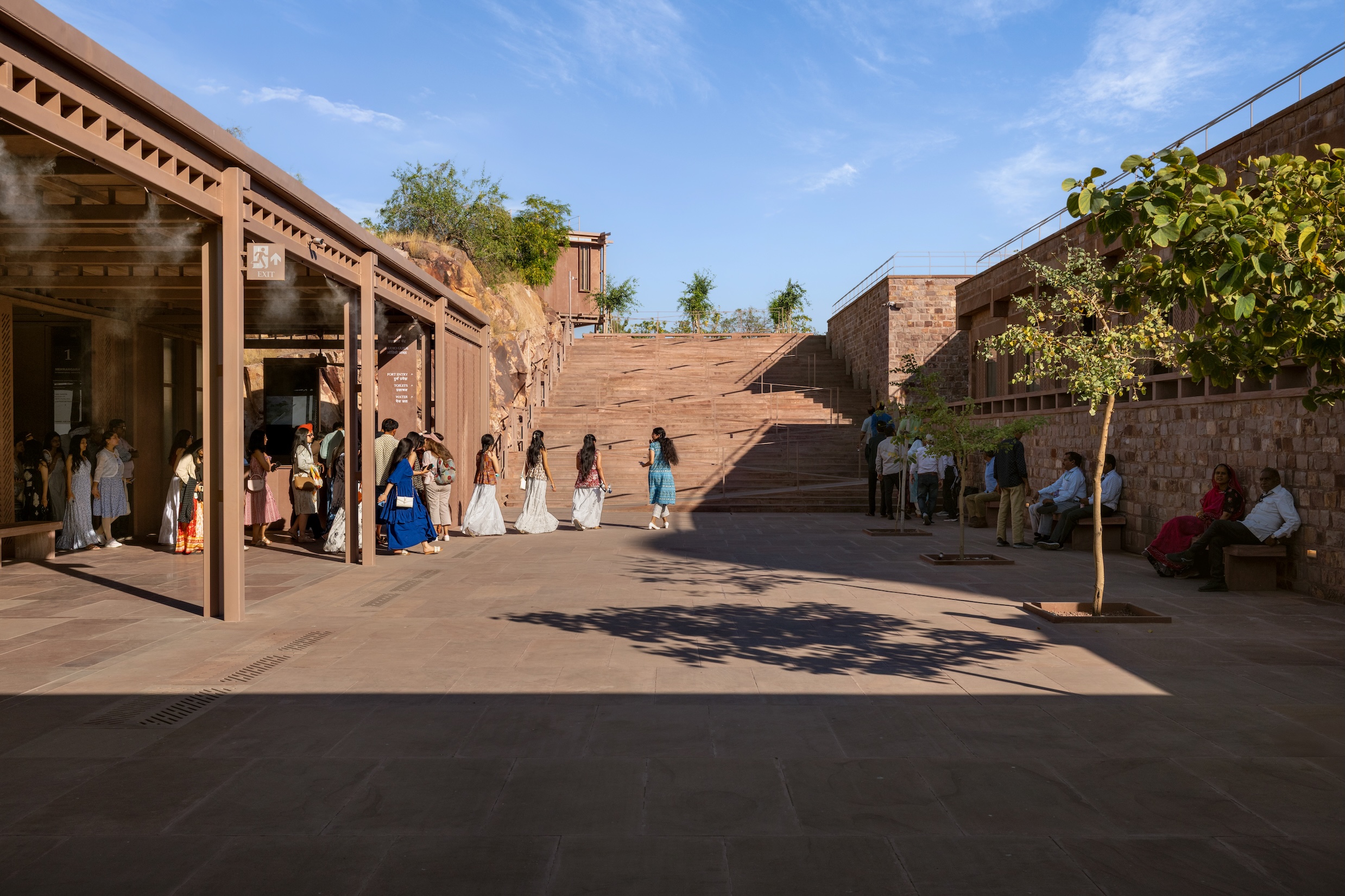 People walk through the Barbara and Gerson Bakar Gateway at UC Berkeley, a stone-paved courtyard with a large staircase leading to an upper level.