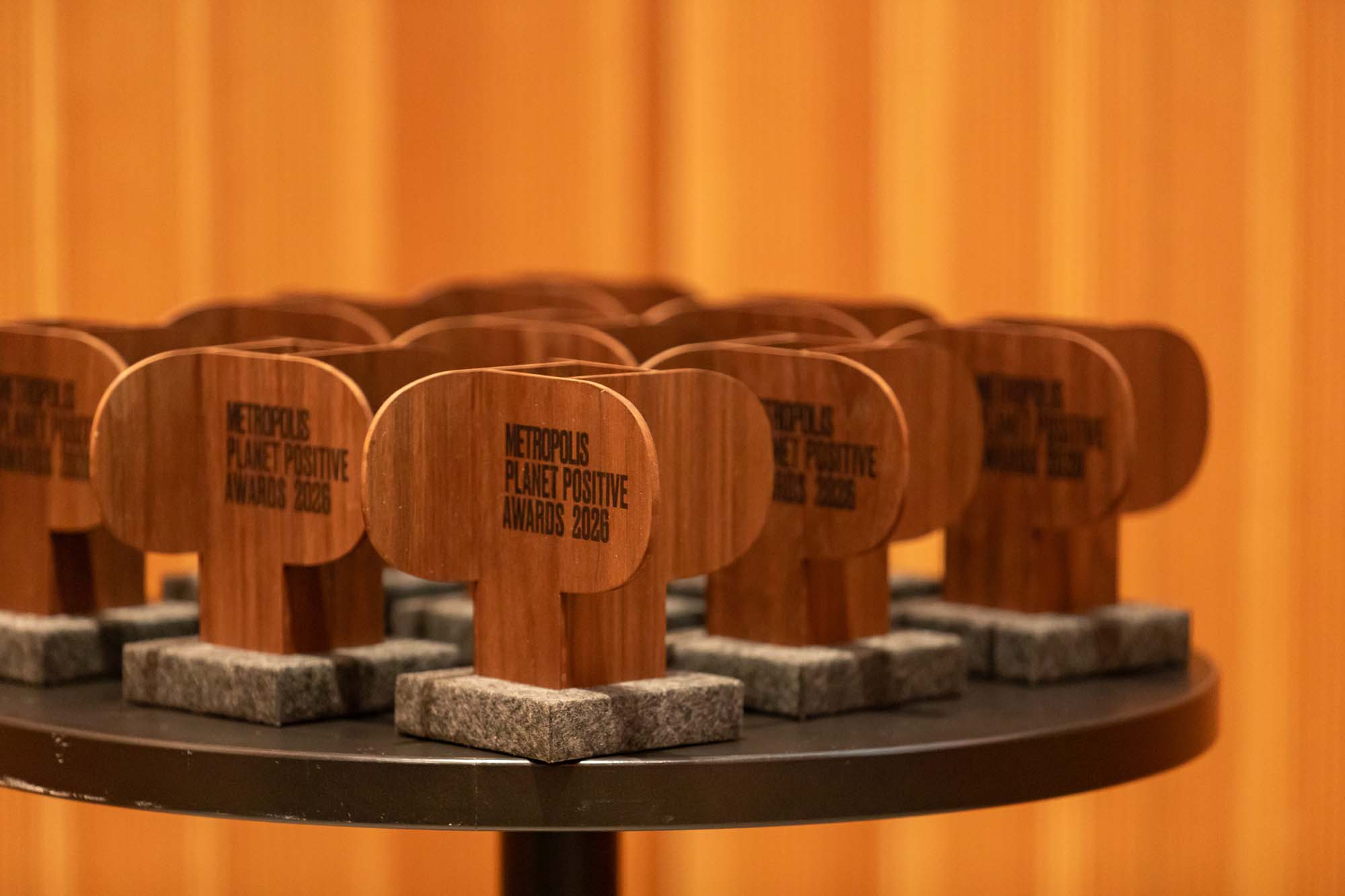 Multiple wooden Metropolis Planet Positive Awards 2026 trophies displayed on a round table.