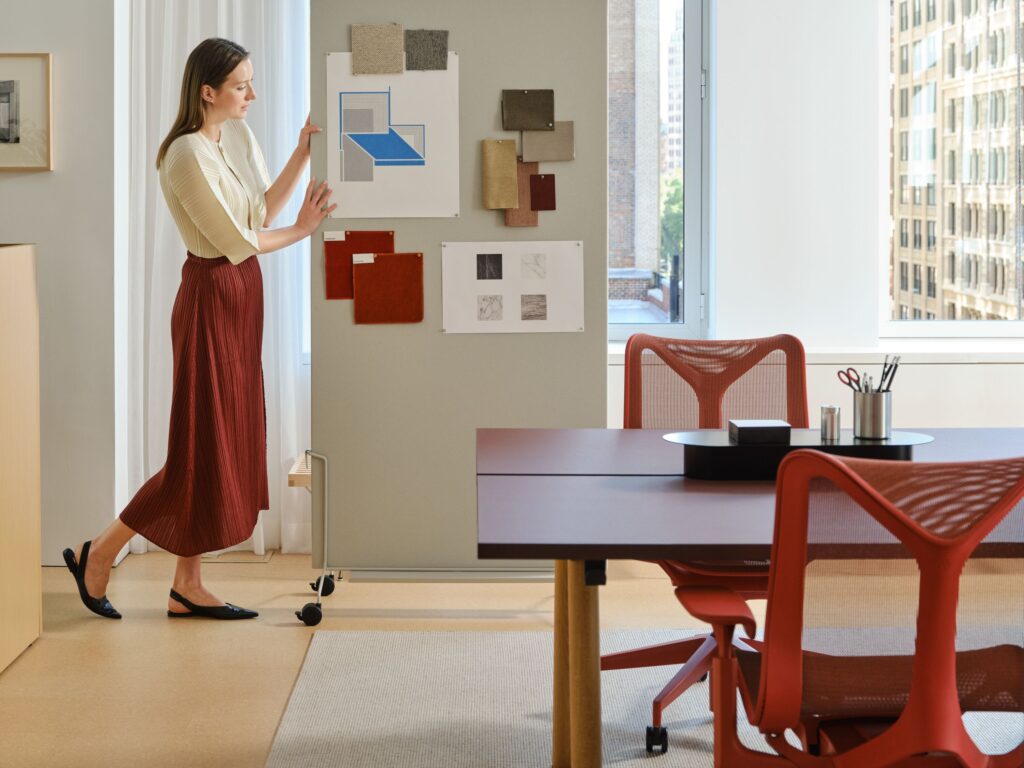 A woman stands in a MillerKnoll office pinning fabric and material swatches onto a portable display board.