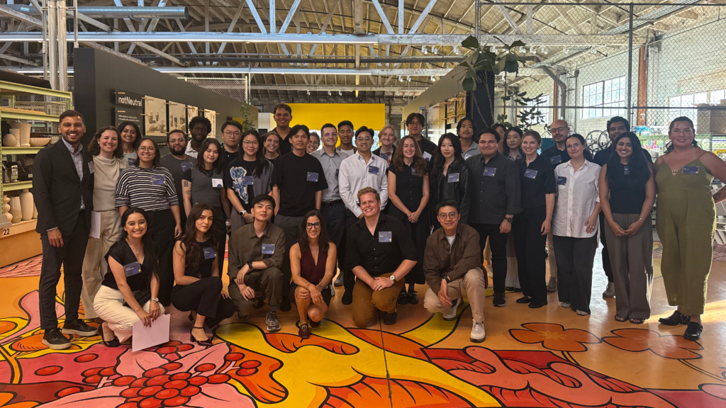 A large group of Arch30 team members posing for a photo in a warehouse-style office space with a decorative painted floor.