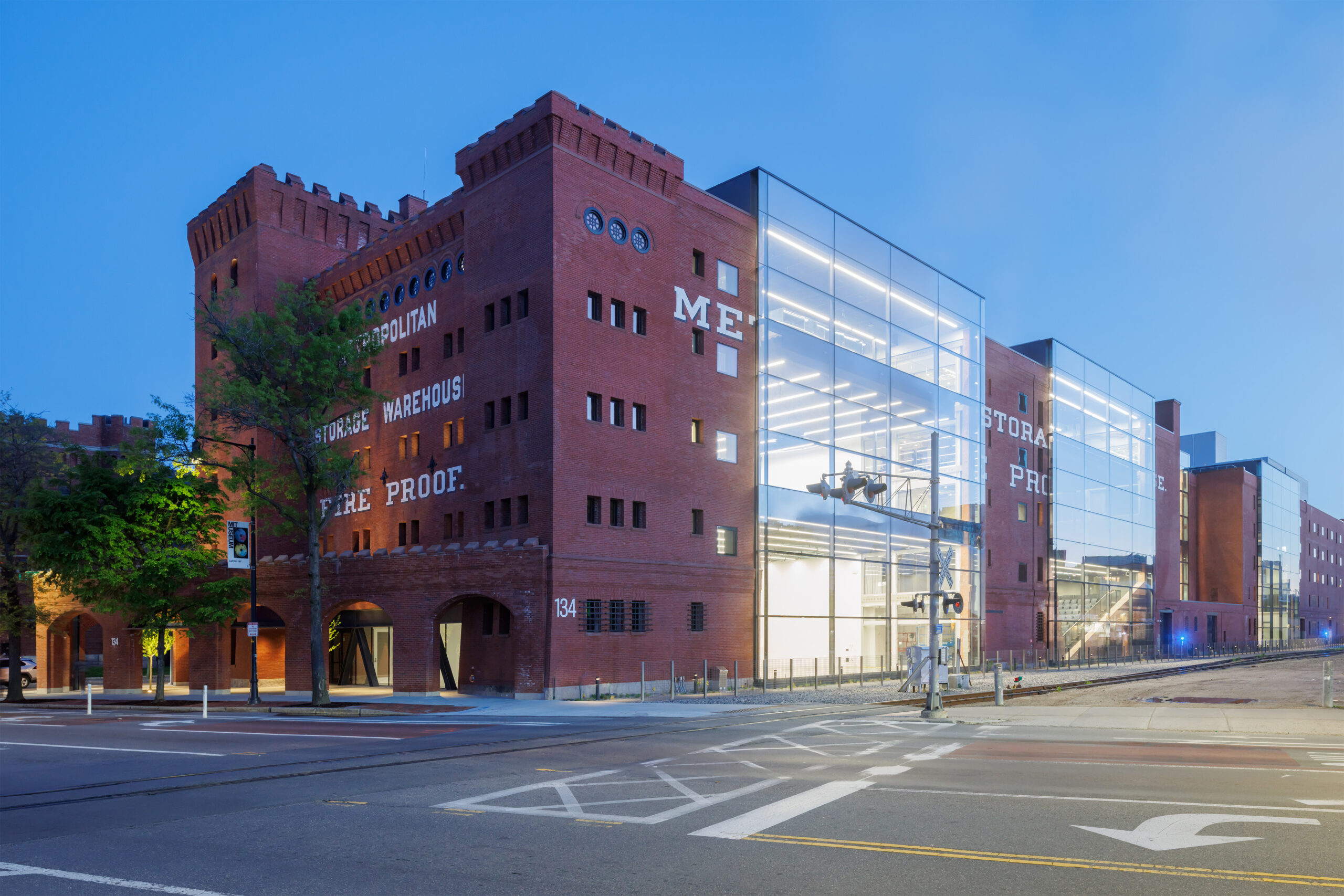 A brick Metropolitan Storage Warehouse building integrated with a modern glass-walled structure at a street corner, captured during MIT Future Fest.