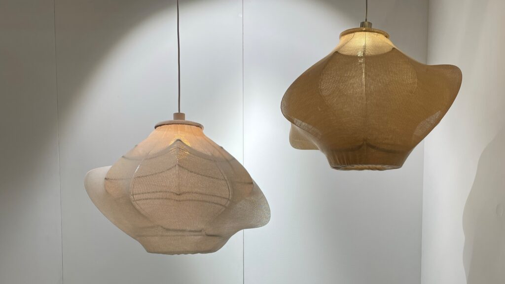 Two sculptural pendant lights with textured, translucent shades hanging against a white wall.