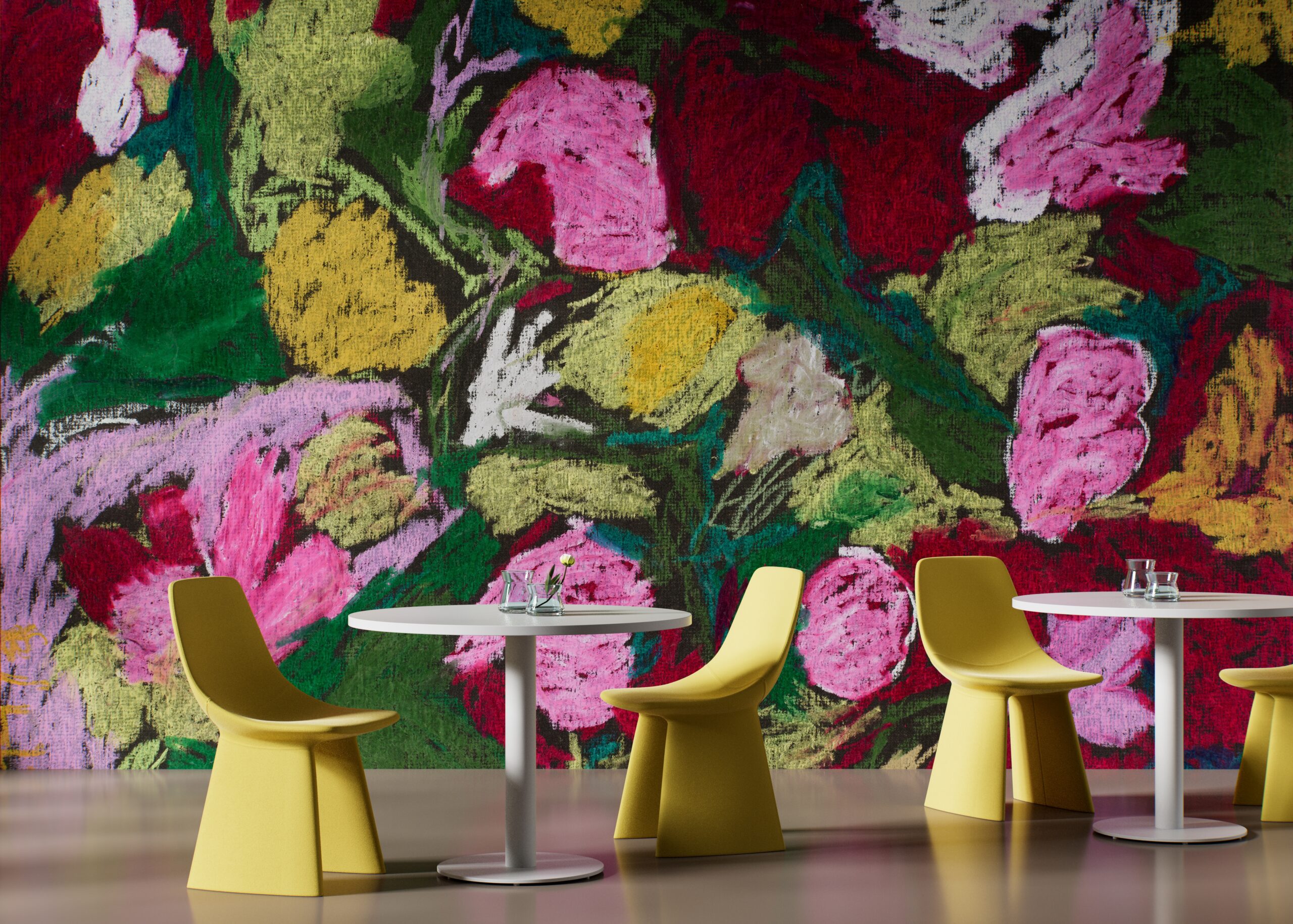 Two small white cafe tables with yellow chairs set against a large mural of colorful abstract flowers.