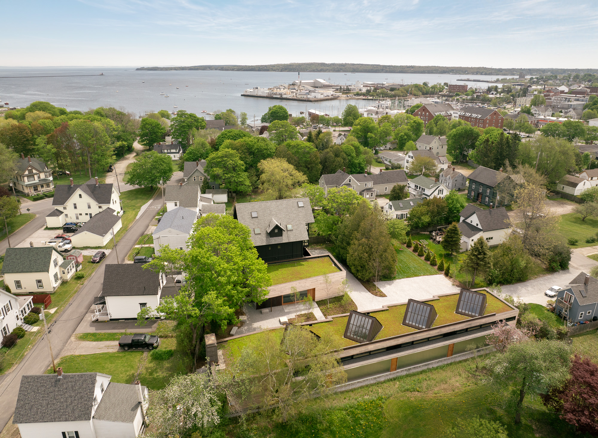 Aerial view of a residential neighborhood near the Ellis-Beauregard Foundation harbor, featuring a modern house with a green roof and three skylights.